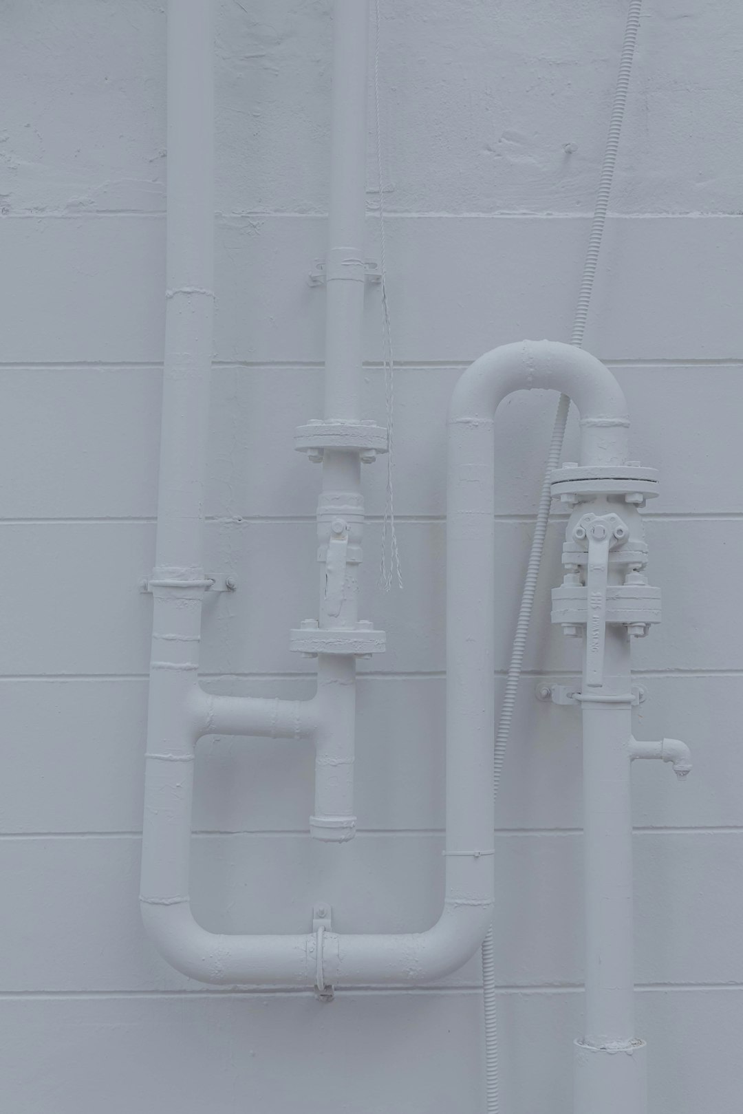 a-white-wall-with-pipes-attached-to-it-nq7g4yva25m